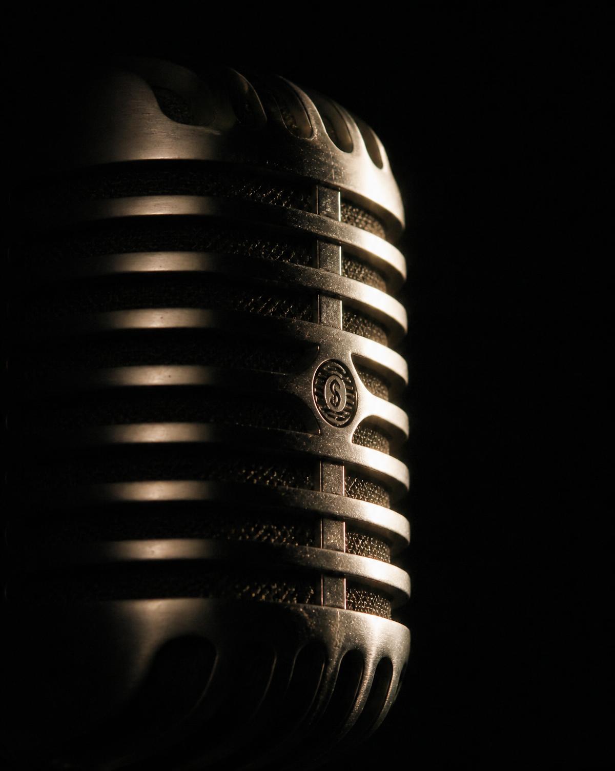 Silver stage microphone lit in darkness